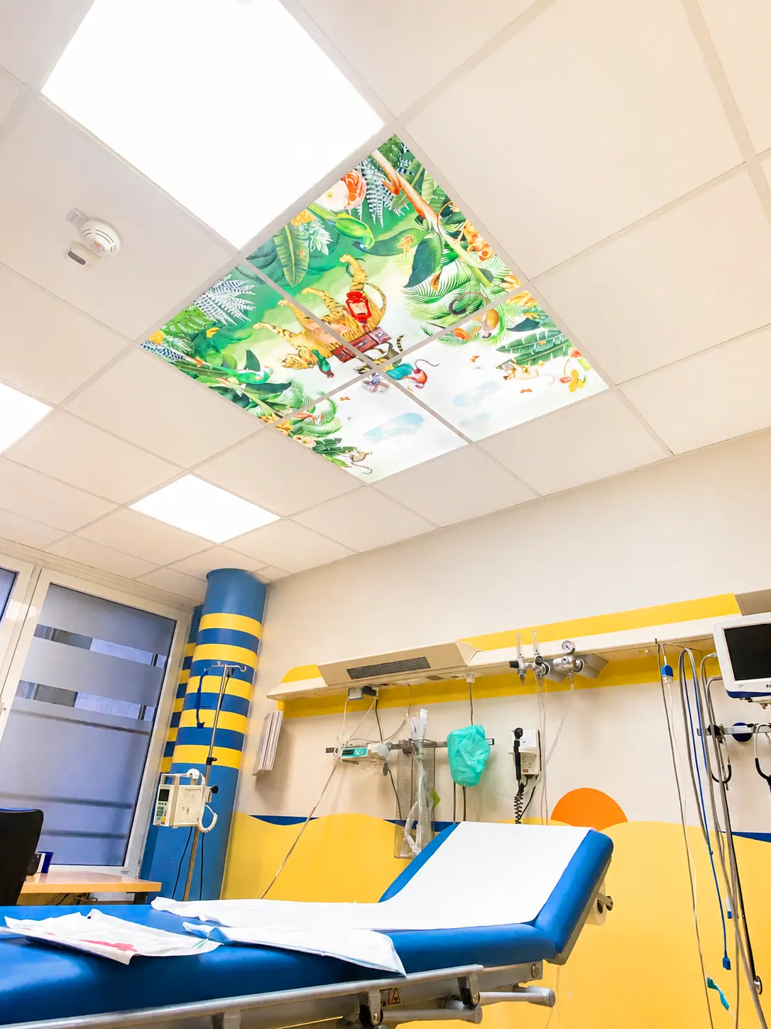 Dentled LED-Fotopaneele mit Naturmotiven, integriert in die Decke einer kindermedizinischen Einrichtung.