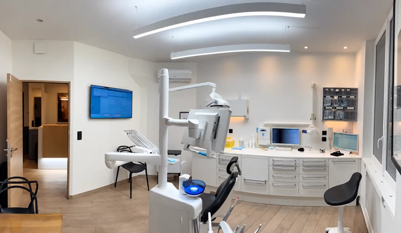 Weitwinkelansicht des Behandlungsraums von Dr. Didier Achour in Paris mit abgehängten Leuchten und Behandlungseinheit.