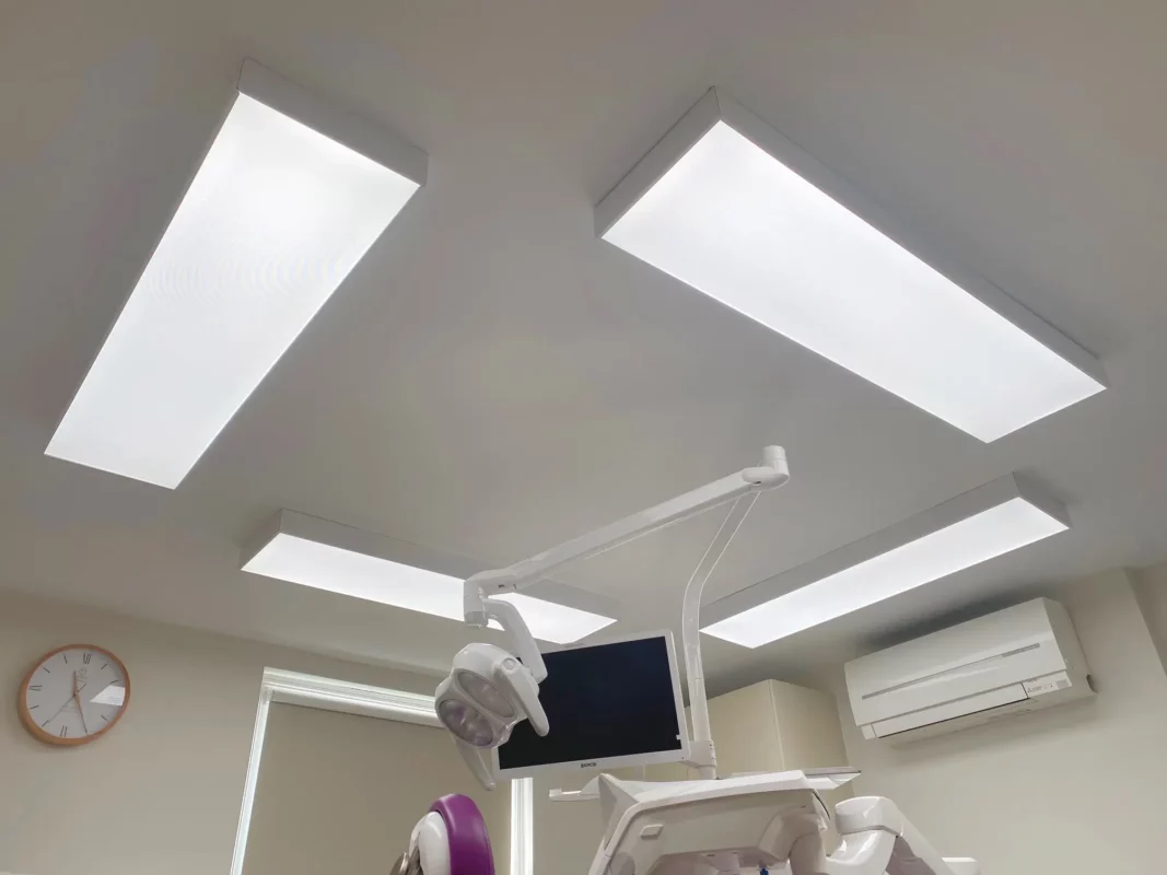 Vier DentLED DL120 LED-Deckenpaneele mit Vollspektrum-Tageslicht in aufgesetzten Rahmen rund um den Behandlungsstuhl bei Priory Dental Care.